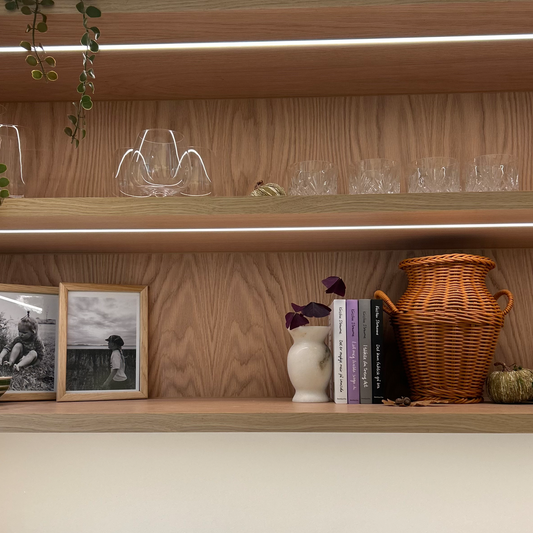 Fire bøker står i ei hylle, der det òg står vakre interiørgjenstandar, og bilete av to små jenter i naturen.